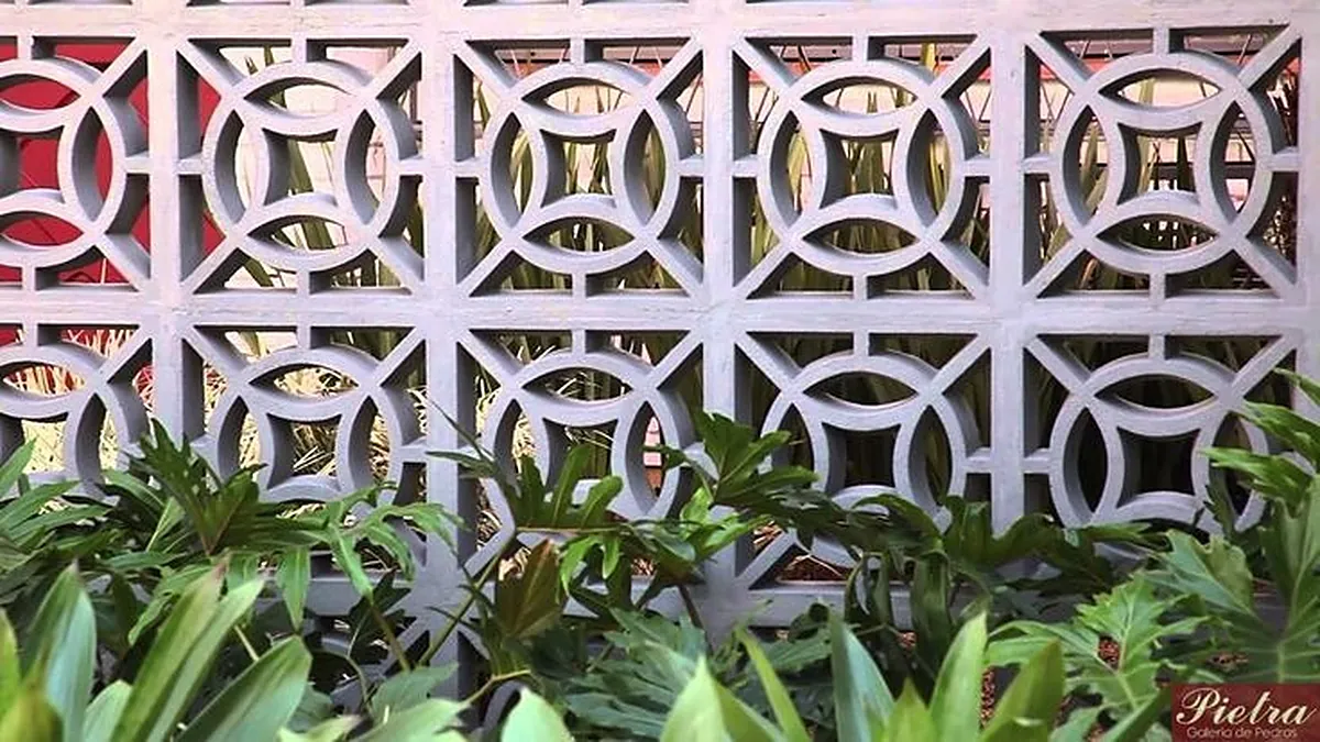 Painel de cobogós círculo brancos com plantas tropicais à frente