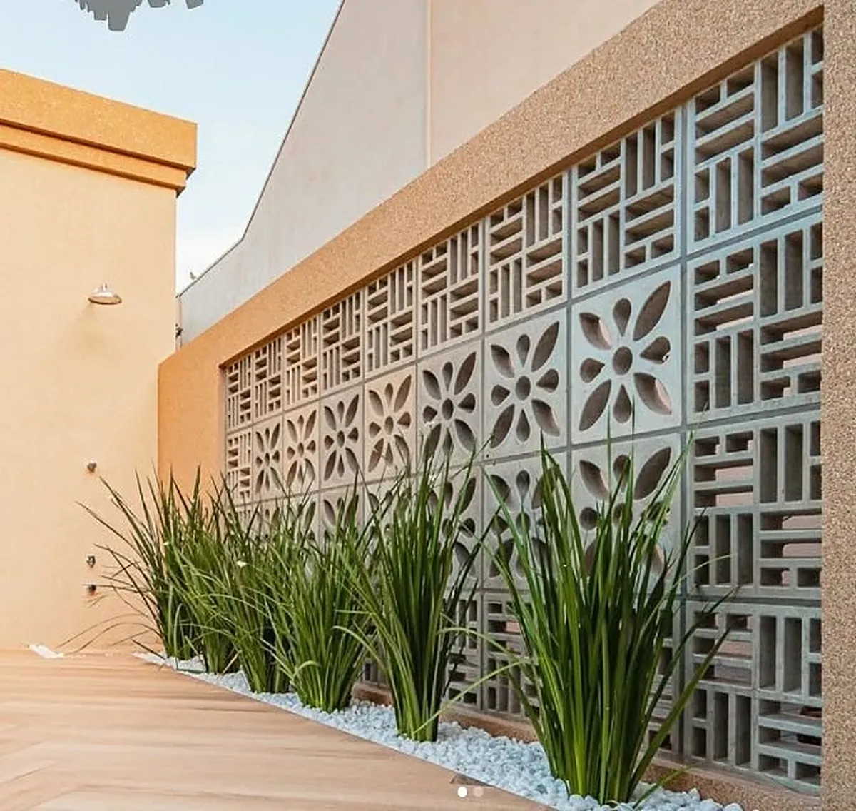 Muro de cobogós de concreto com desenhos variados e canteiro de plantas na base