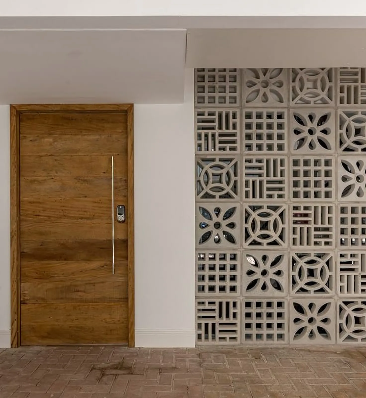 Fachada residencial com porta de madeira e painel de cobogós de concreto